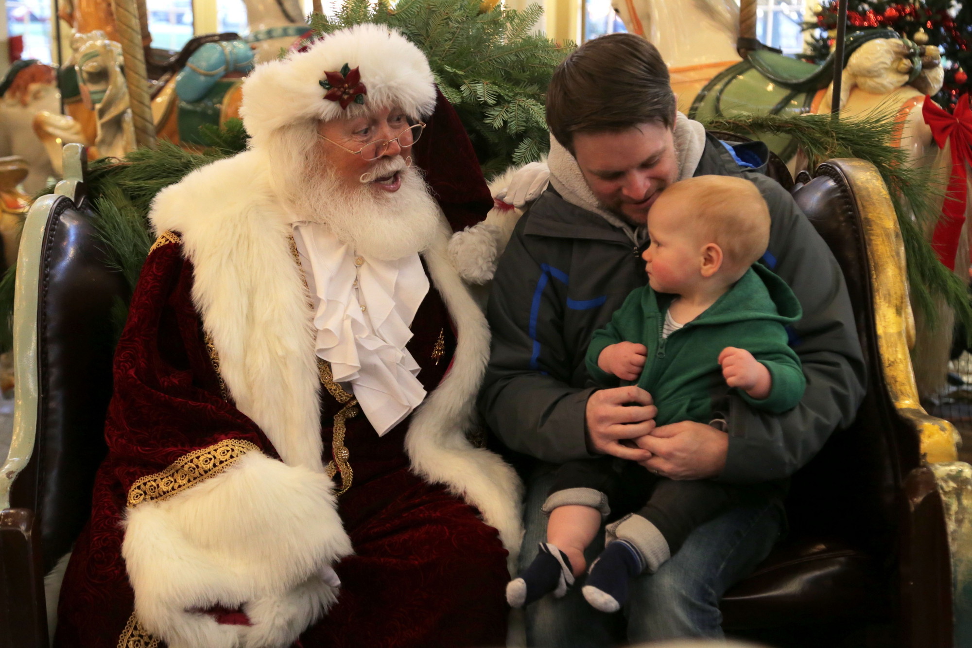 One year old Drew Coutu sits with Santa Claus inside the Crescent Park Carousel.