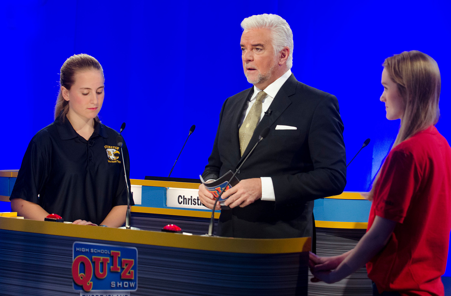 Actor John O'Hurley, the host of High School Quiz Show: Rhode Island, prepares to ask a question to Barrington's Christina Curran (left) and a student from Exeter-West Greenwich.