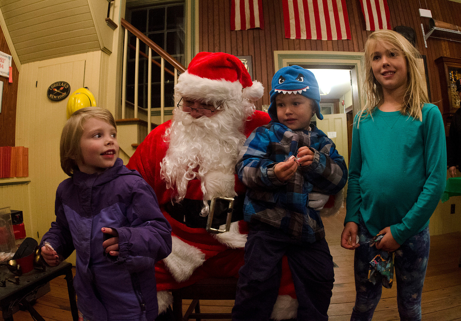 From left, Lily Deluck, 4, Finn Caldwell, 4, and Keava Caldwell, 8, tell Santa what they want for Christmas in the Fire Museum.