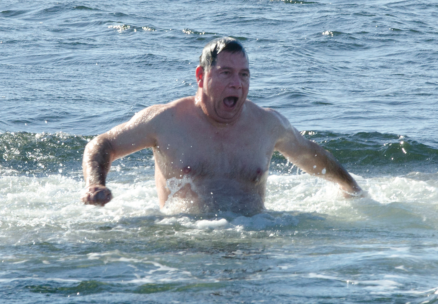Todd Jeszale of Tiverton grimaces on his way out of the water at Tiverton’s Grinnell’s Beach. He went in alone at noon after the penguin plunge was cancelled for safety reasons.