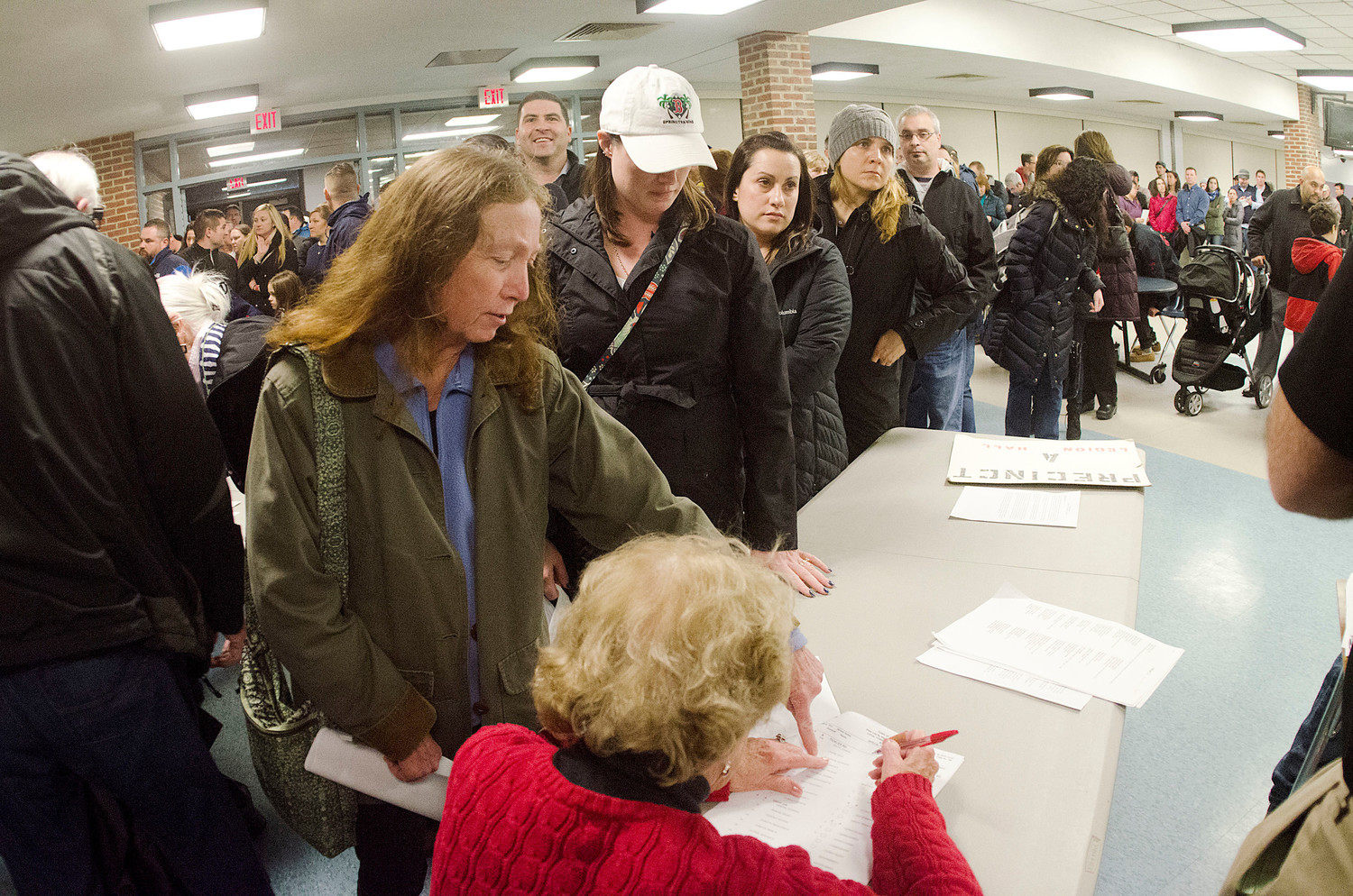 Kathleen Cummings (left) signs in before the meeting. It took over an hour to sign in the 1000 plus voters.