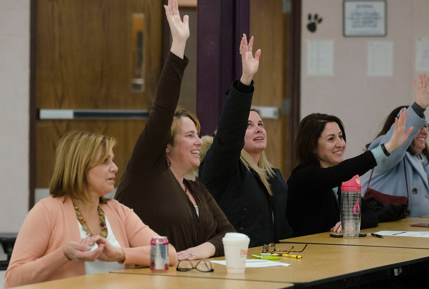 From left, Nicki Tyska, Marie Knapman, Shelia Ellsworth, Amy Bratos and others give a show of hands for those who would go to the state house in an attempt to gain more funds from the state.