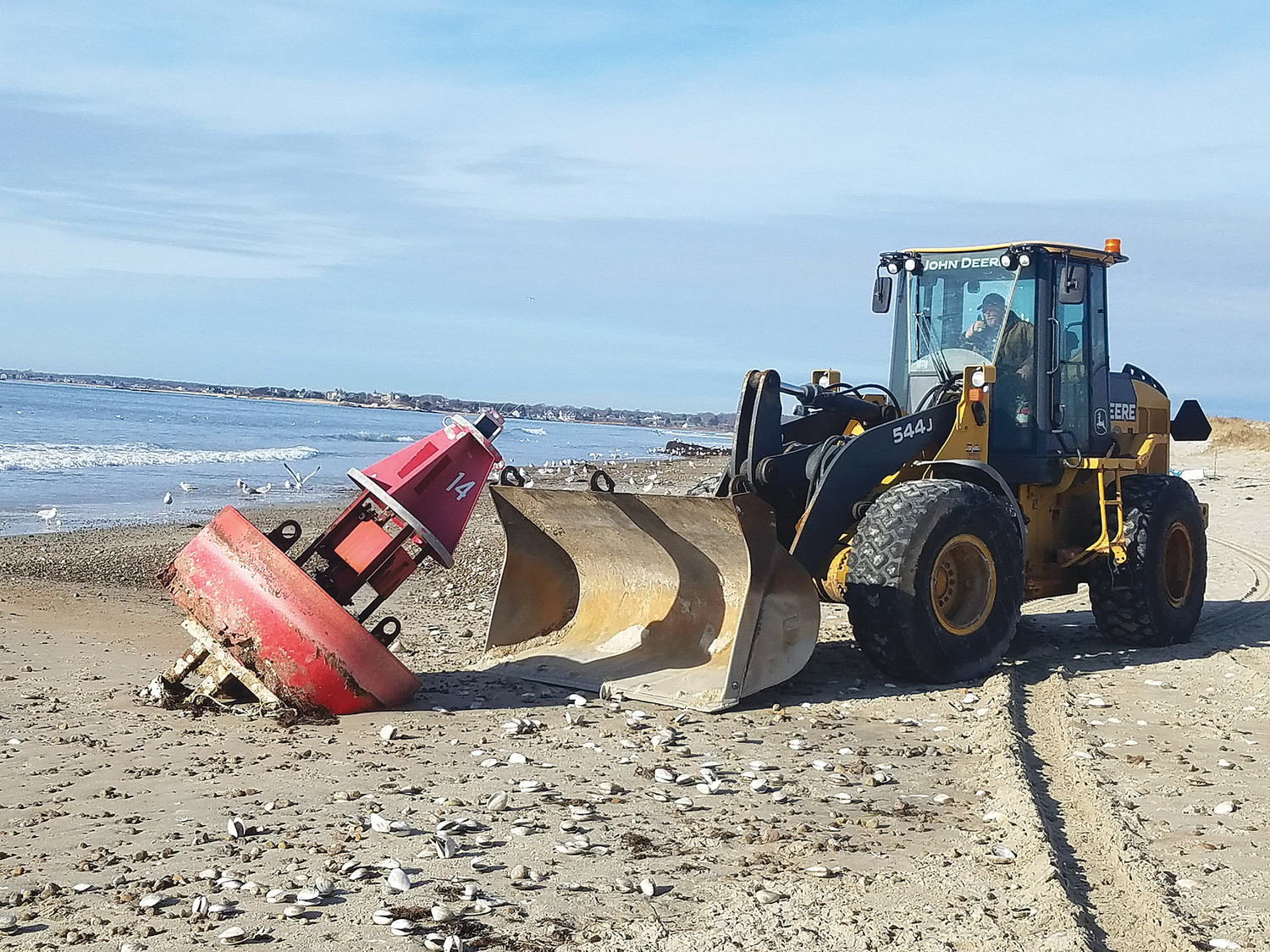 A Highway Department front end loader drives up to beached buoy #14, high and dry on the outer beach south of Bridge Street last week. Westport Marine Services photo.