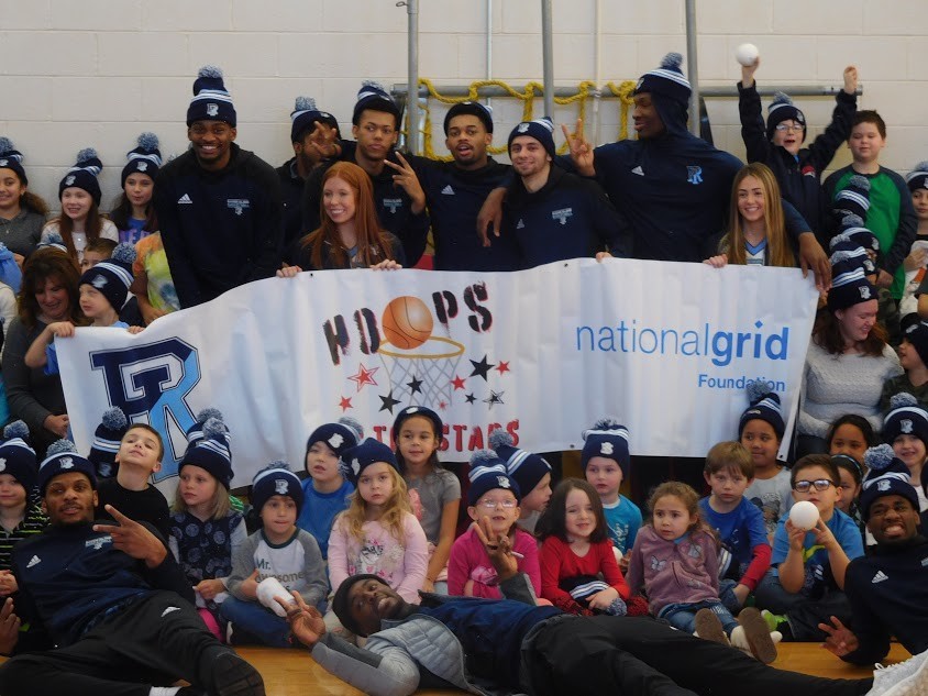 URI team members (that’s Stanford Robinson lying across the foreground) and cheerleaders pose for a group shot and a ‘Let’s Go Rhody’  chant with their Pocasset School fans.